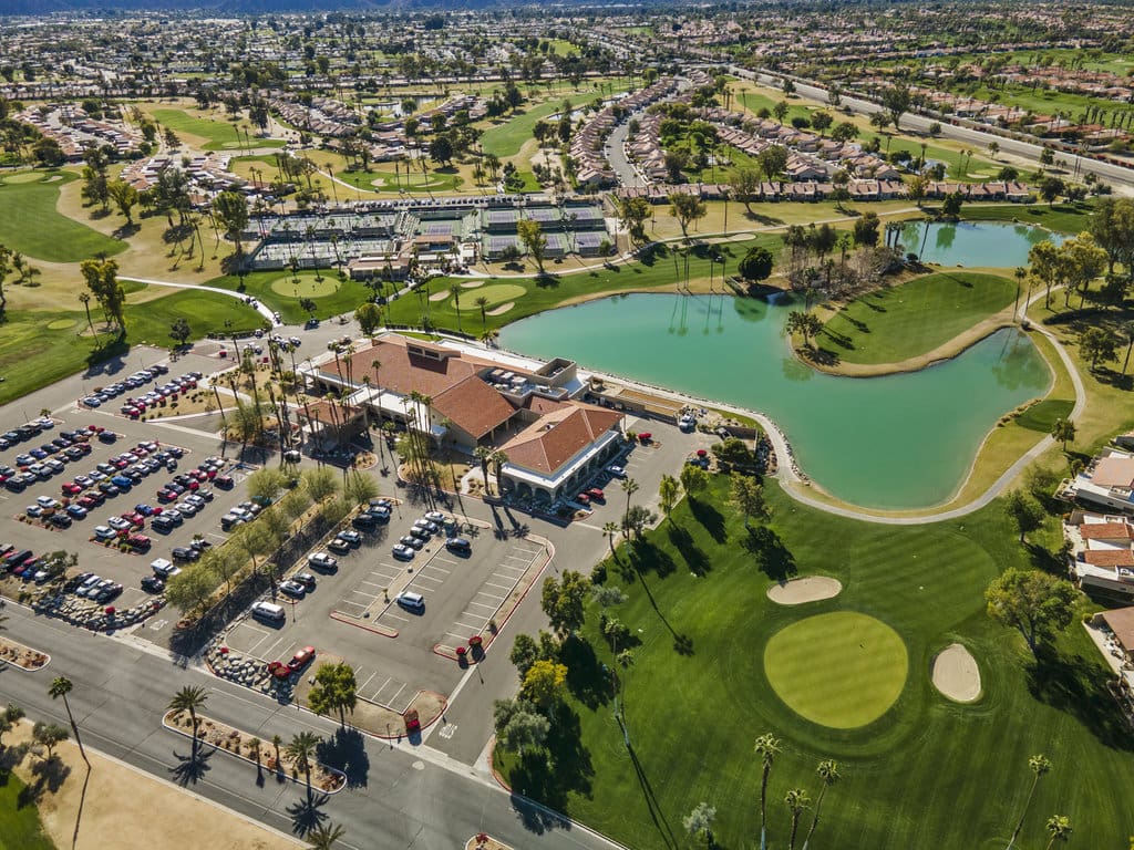 AerIal View of 41443 Inverness Way with pond, parking lots, houses and palm trees